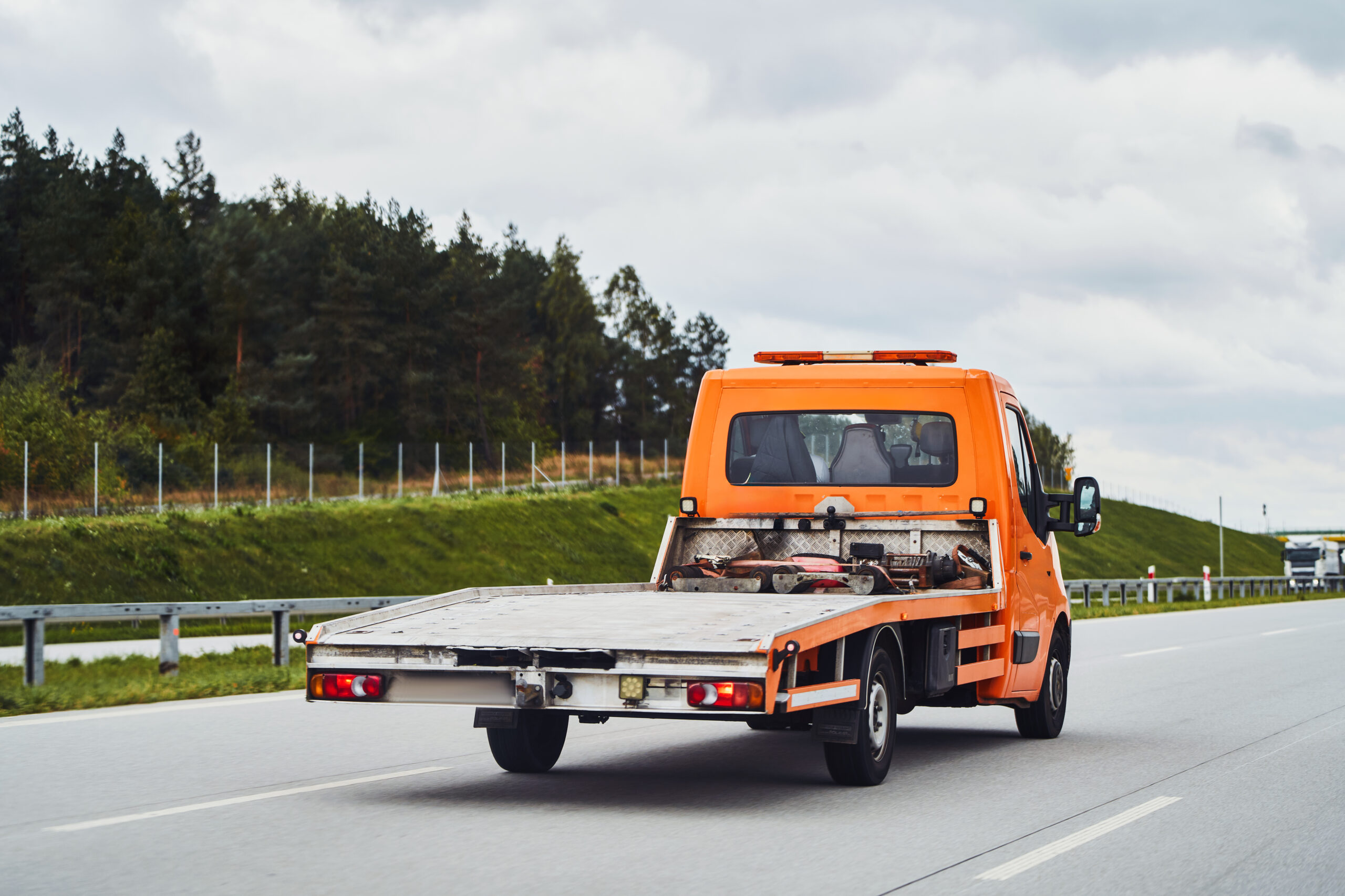 car-carrier-tow-truck-driving-fast-road-with-no-vehicle-loaded-modern-new-tow-truck-transporter-with-space-text-highway-summer-landscape