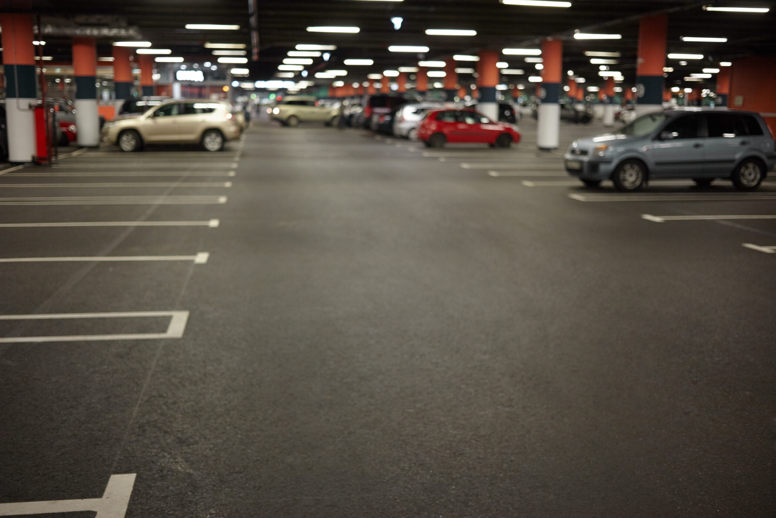 Horizontal picture of car parking or underground garage interior with neon lights and autocars parked. Buildings, urban constructions, space, transportation, vehicle and night city concept