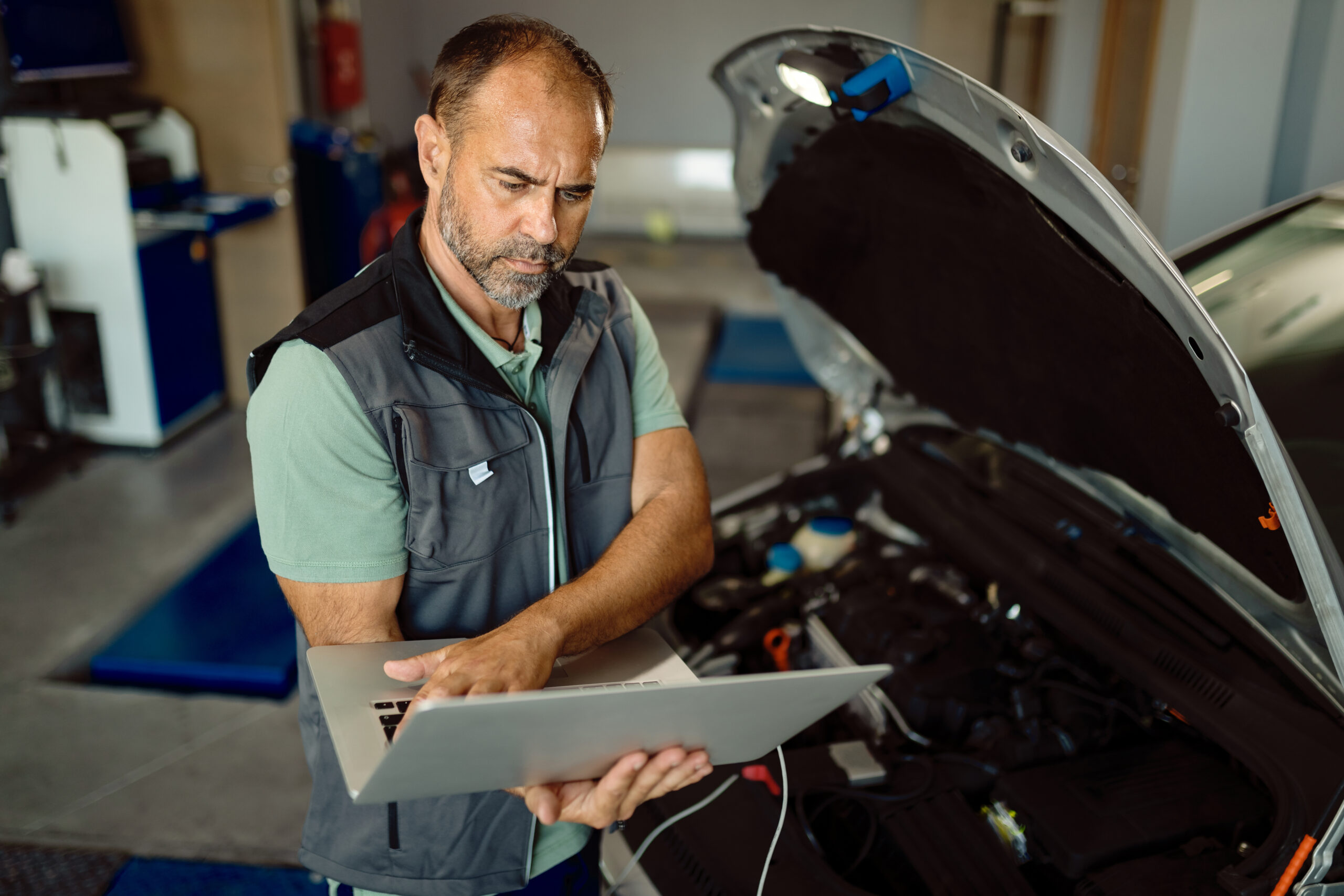 Car mechanic using laptop while running engine diagnostic at rep